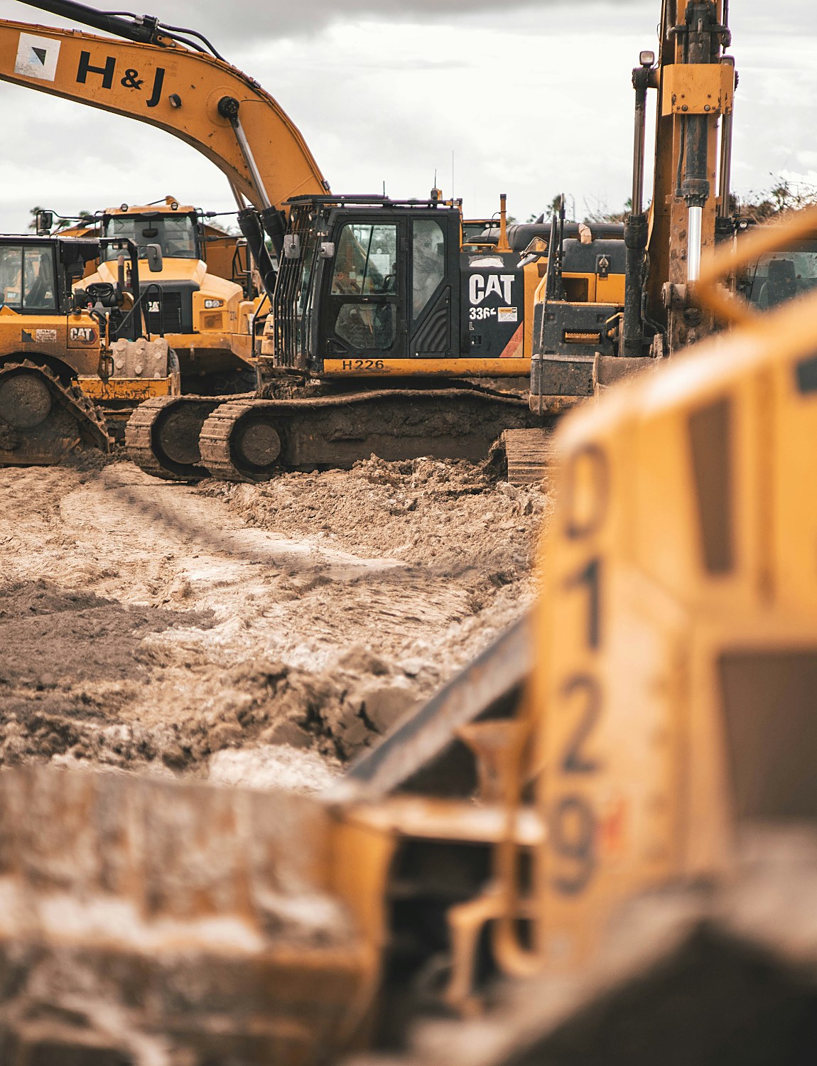 Excavators and construction equipment lined up on a muddy job site