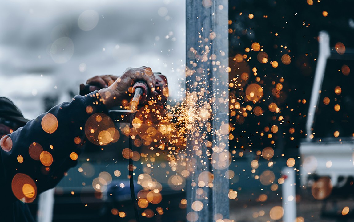 Close-up of welding sparks flying from a grinder against a steel beam