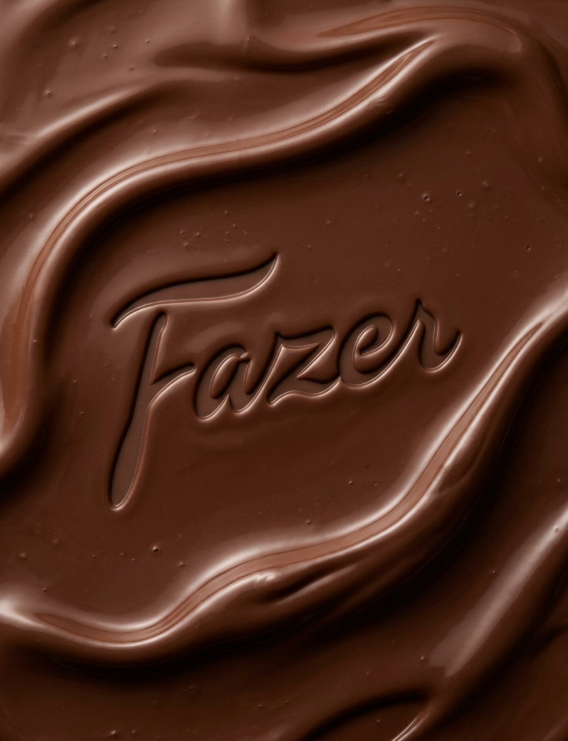 Fazer wordmark embossed into molten dark chocolate, close-up detail shot