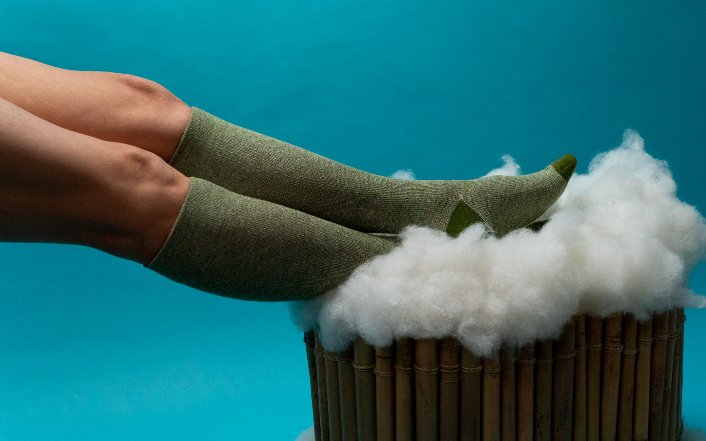 Wellow compression socks in bamboo-yarn green, resting on a cloud of bamboo fibre