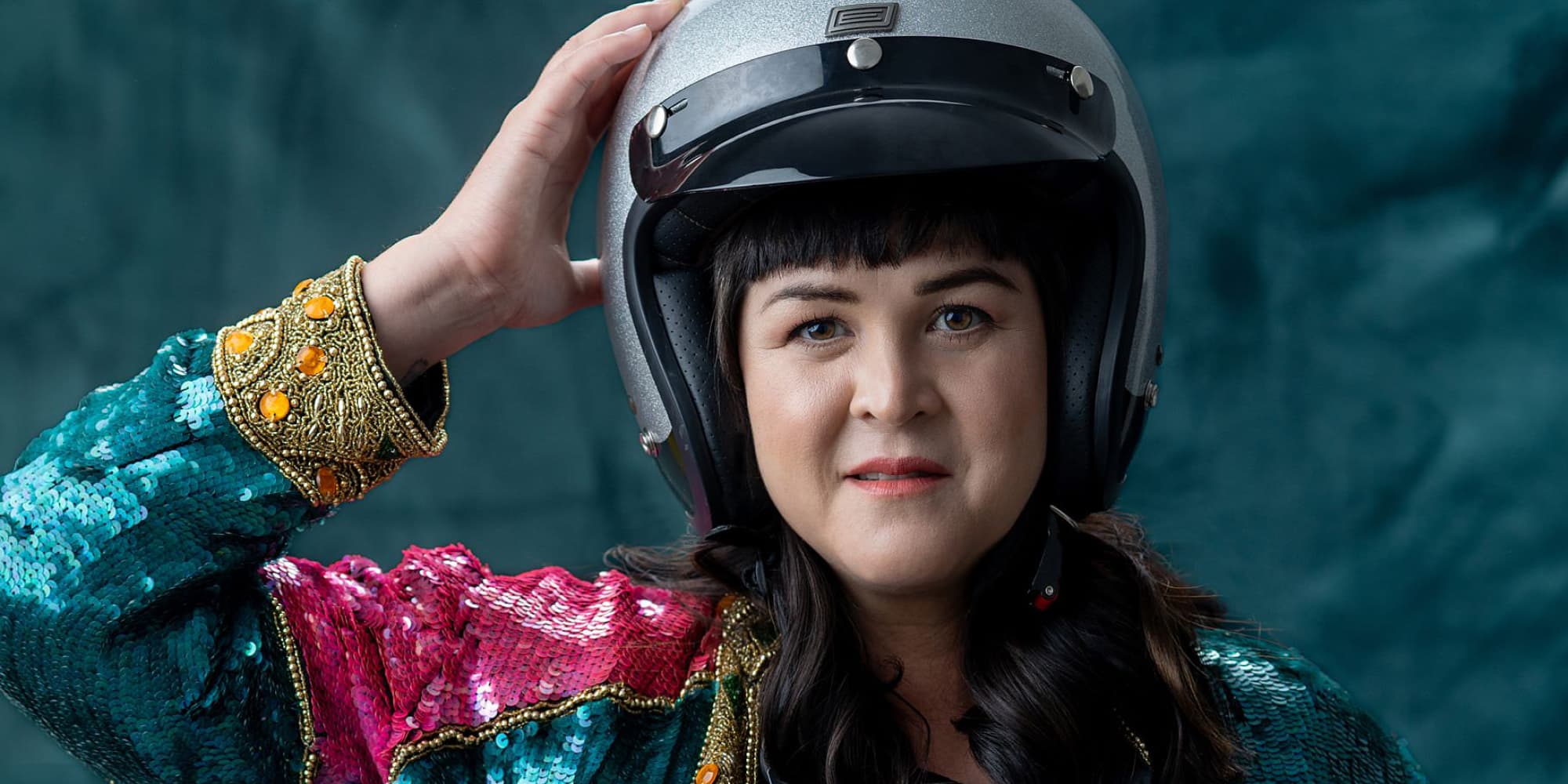 Portrait of artist Jalita S. Aspelin wearing a silver motorcycle helmet and a vibrant, sequined maximalist jacket, symbolizing the "point of no return" and the bold transition into her new creative era.